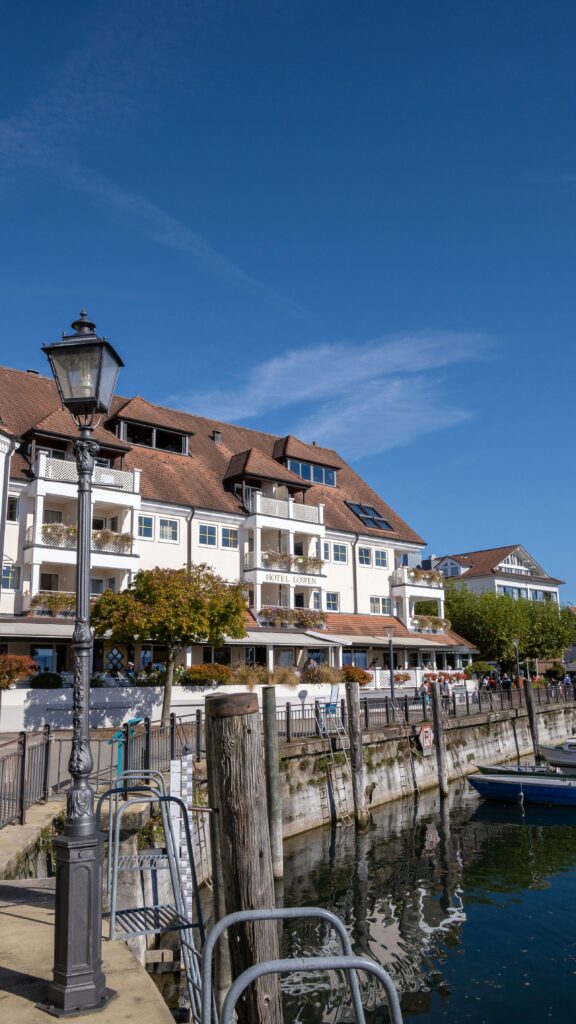 Hotel Löwen mit historischer Fassade am Bodensee-Ufer, Laterne und Bootsanlegestelle im Vordergrund