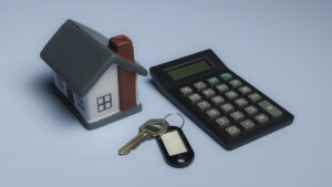 Miniaturhaus mit Schlüssel und Taschenrechner symbolisiert die Berechnung der Hausverkauf Kosten